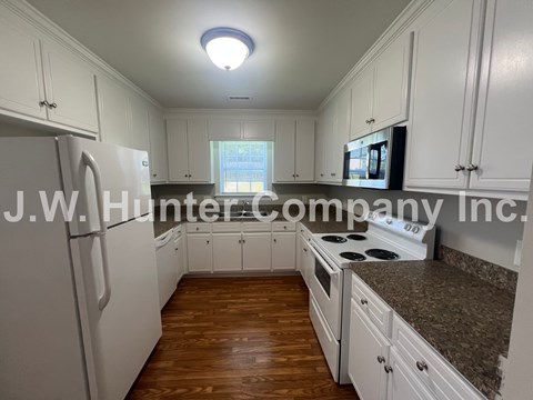 A kitchen with white cabinets and a refrigerator.