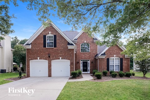 a brick house with two garage doors and a driveway