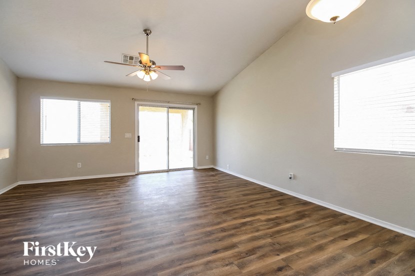 the spacious living room with wood flooring and a ceiling fan