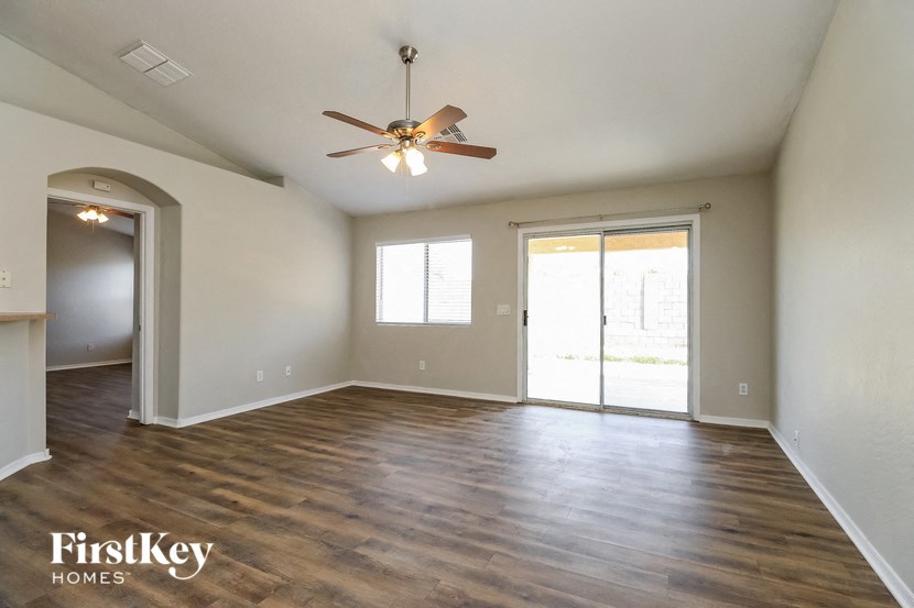 an empty living room with wood floors and a ceiling fan