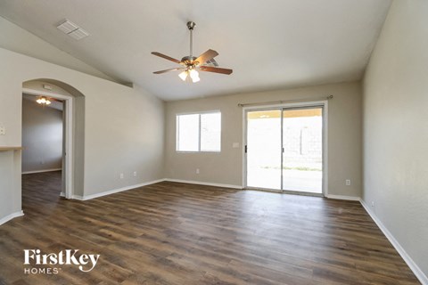 an empty living room with wood floors and a ceiling fan