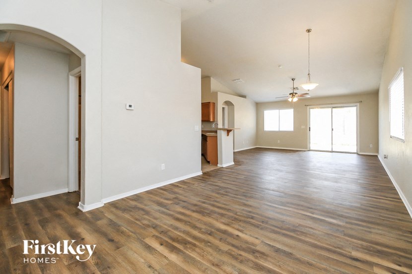an empty living room and kitchen with wood flooring