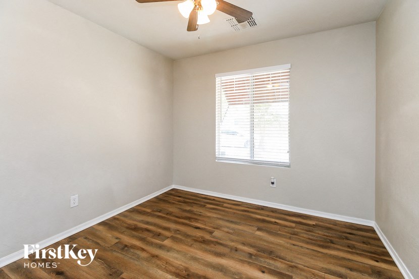 the living room of an empty home with wood flooring and a window
