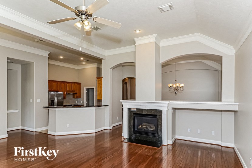 an empty living room with a fireplace and a ceiling fan