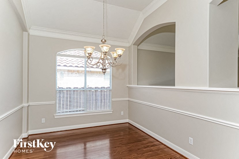 an empty dining room with a window and a chandelier