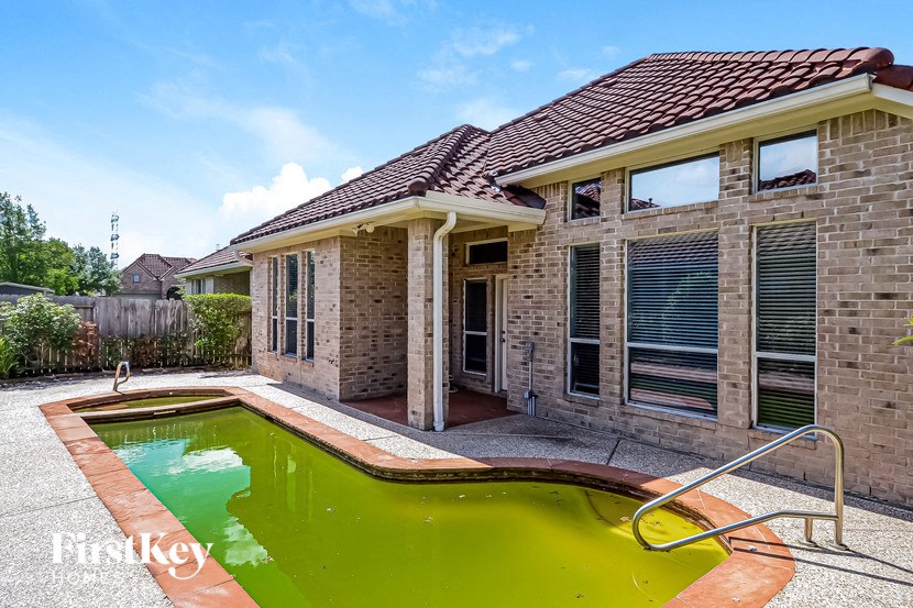 a pool in front of a brick house with a house pool