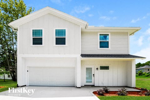A white house with a black roof and a garage door.