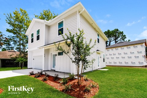A white house with a tree in front of it.