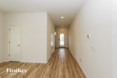 A long hallway with wood floors and white walls.
