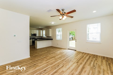 A spacious room with wooden flooring and a ceiling fan.
