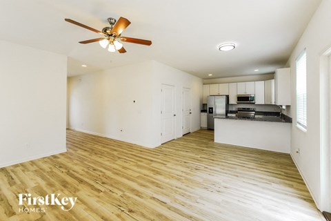 A spacious kitchen and living room with wooden floors and a ceiling fan.