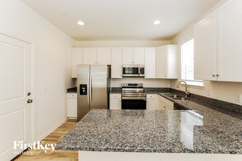A kitchen with granite countertops and white cabinets.