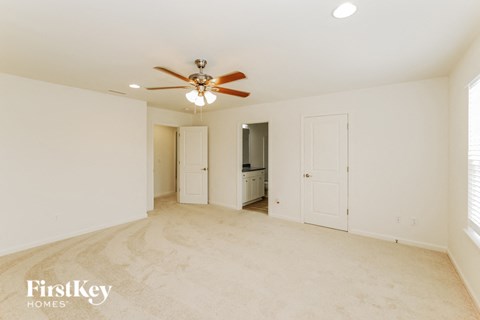 A spacious room with a ceiling fan and lighting fixtures.