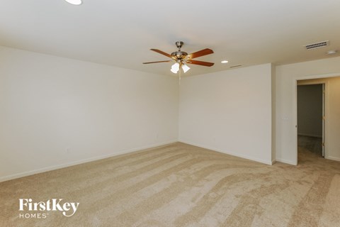 A room with a carpeted floor and a ceiling fan.