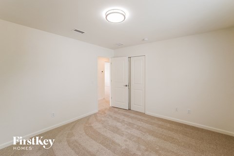 A carpeted room with a white door and a light on the ceiling.