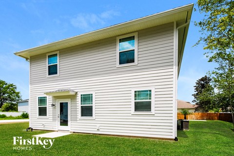 A house with a white siding and a brown roof with a small porch.