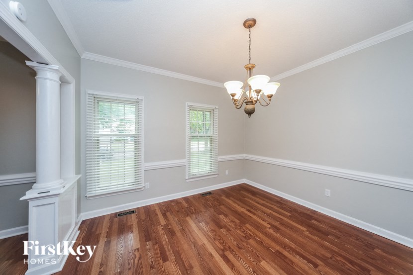 an empty dining room with wood floors and a chandelier