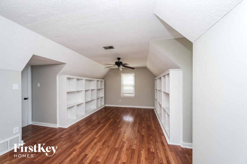 an empty room with a ceiling fan and book shelves