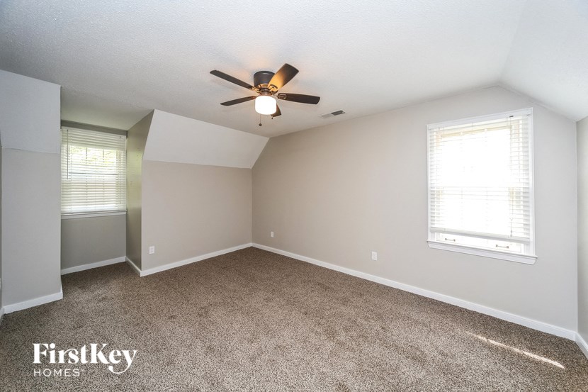 an empty bedroom with a ceiling fan and window