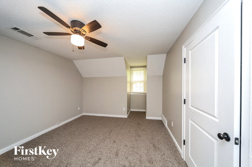 an empty bedroom with a ceiling fan and a closet