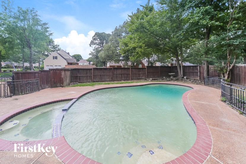 a swimming pool with a fence around it and trees