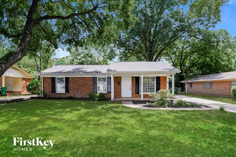 a small brick house with a lawn and trees