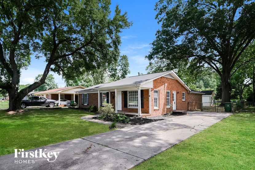 a brick house with a driveway and some trees