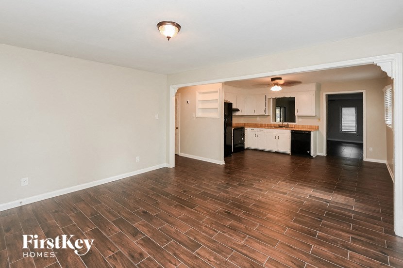 an empty living room and kitchen with wood flooring