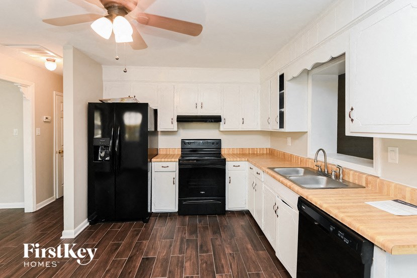 a kitchen with white cabinets and a black refrigerator