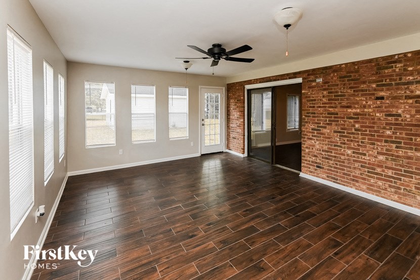 an empty living room with a brick wall and a ceiling fan