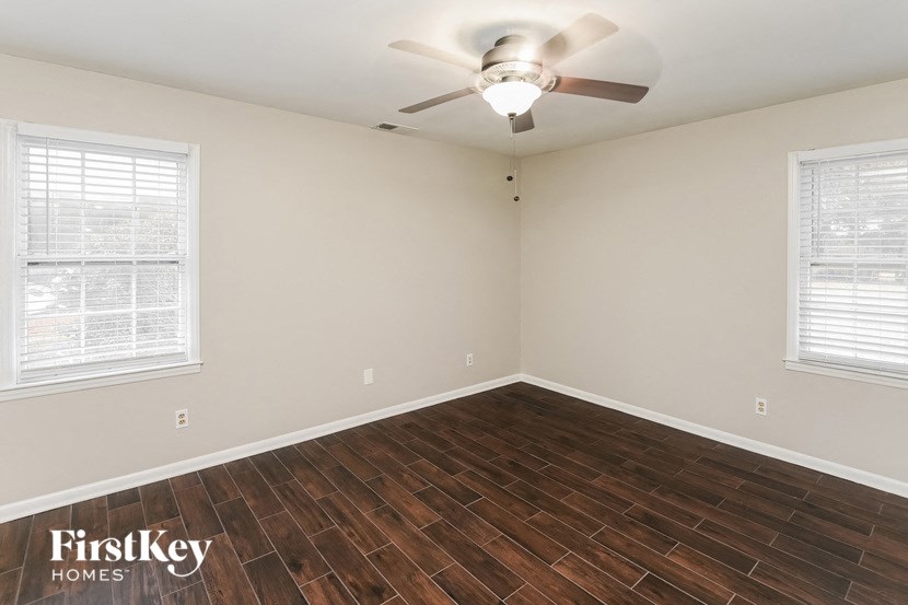 an empty room with a ceiling fan and two windows