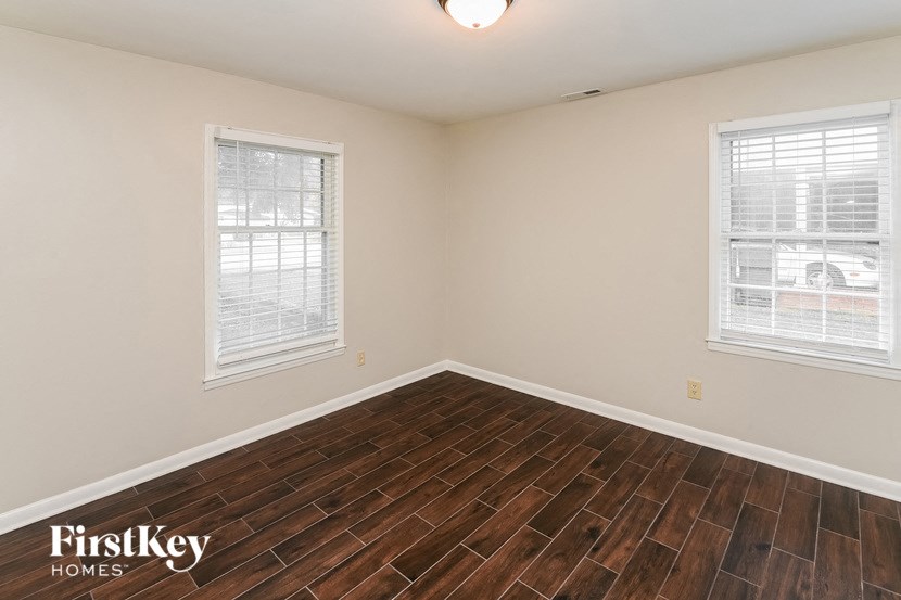 the living room of a home with wood flooring and two windows