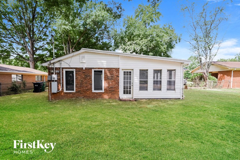 a small white and brick house in a grassy yard