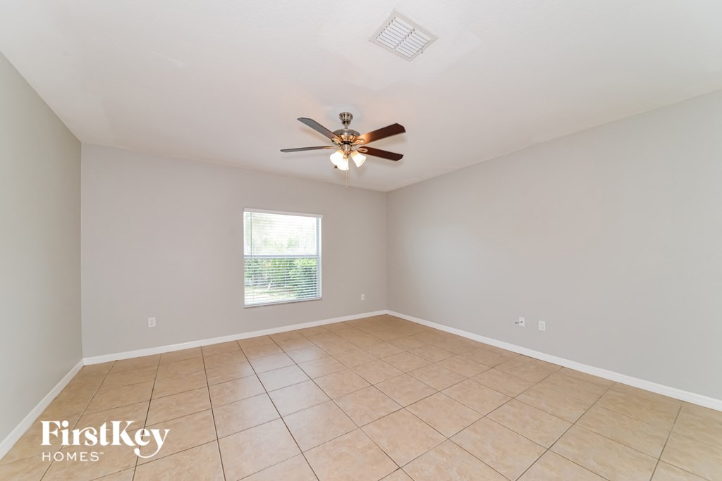 an empty living room with a ceiling fan and tiled floors