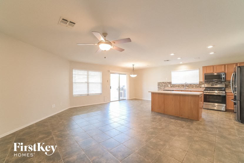 an empty kitchen and living room with a ceiling fan