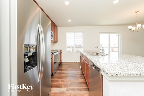 A modern kitchen with a stainless steel refrigerator and wooden floors.