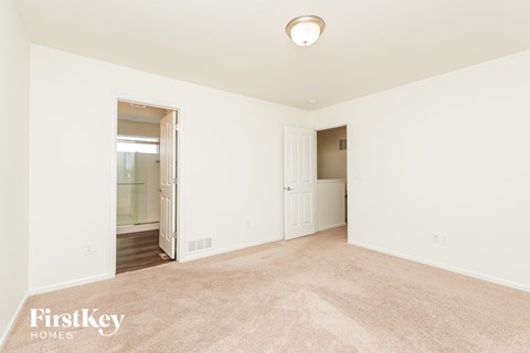 A spacious room with a carpeted floor and a doorway leading to another room.