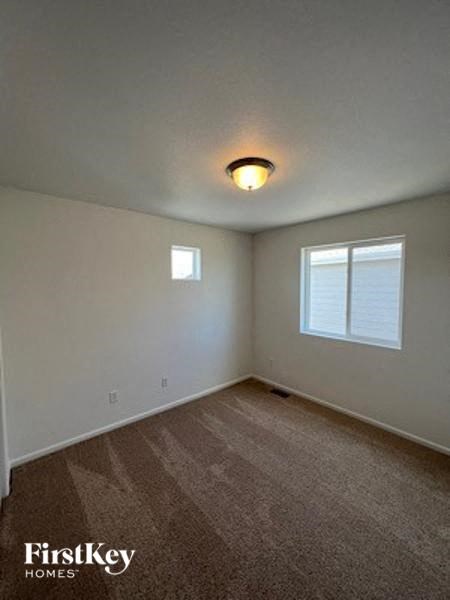 A carpeted room with a window and a light on the ceiling.