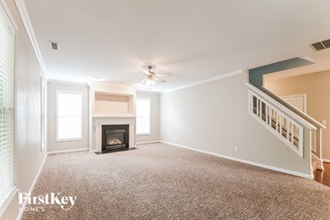 A spacious living room with a fireplace and a staircase.
