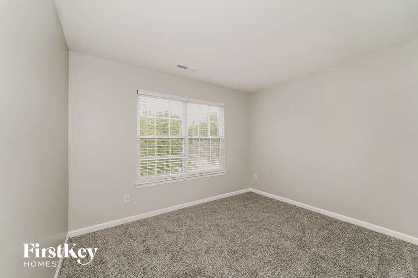 an empty bedroom with a window and carpet