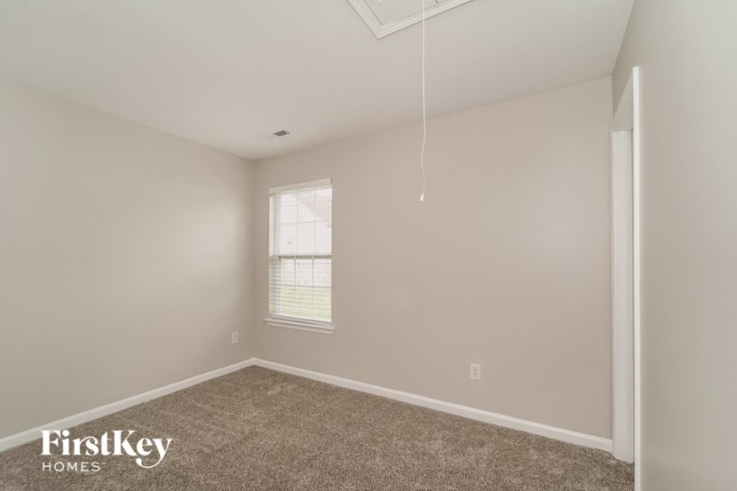 the bedroom of a home with carpet and a window