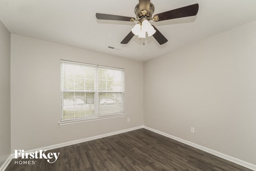 an empty bedroom with a ceiling fan and a window