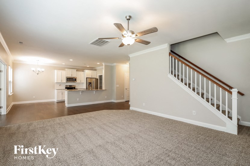 an empty living room and kitchen with a ceiling fan