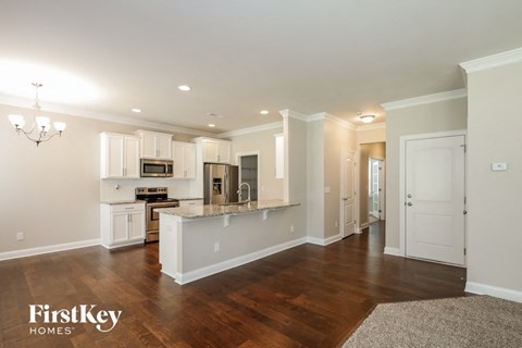 an open kitchen and living room with white cabinets and a counter top