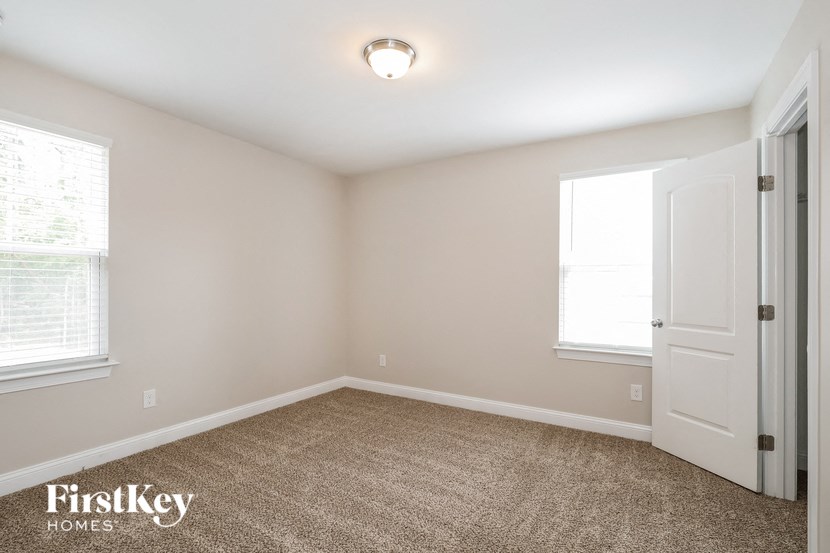the bedroom of a home with a white door and carpet