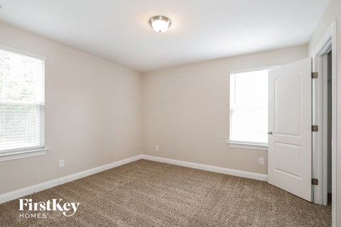 the bedroom of a home with a white door and carpet