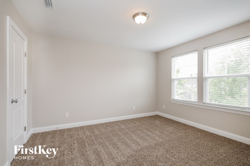 a bedroom with two windows and a carpeted floor