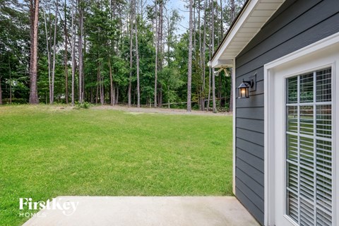 a side view of a house with a lawn and trees