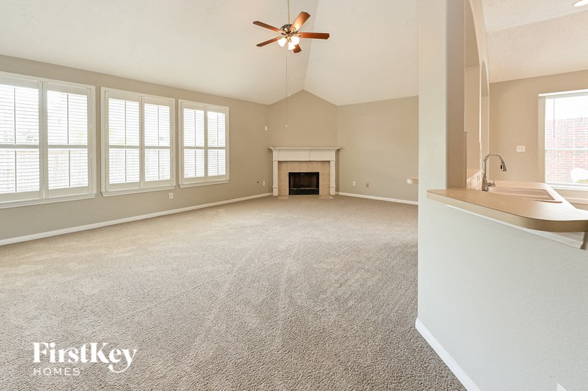 an empty living room with a ceiling fan and a fireplace