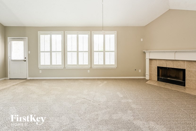 an empty living room with a fireplace and windows